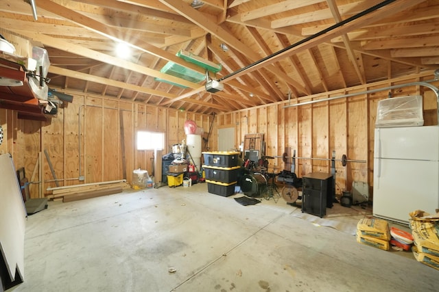 garage featuring a garage door opener, water heater, and white refrigerator