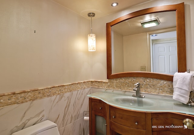 bathroom featuring tile walls, vanity, and toilet