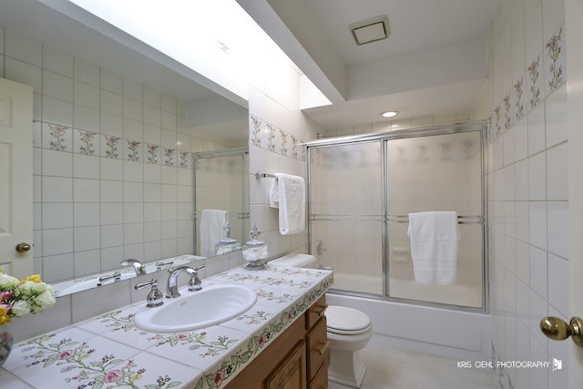 full bathroom with vanity, bath / shower combo with glass door, and toilet