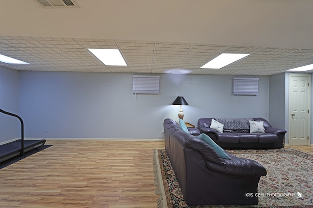 living room with light hardwood / wood-style flooring and a paneled ceiling