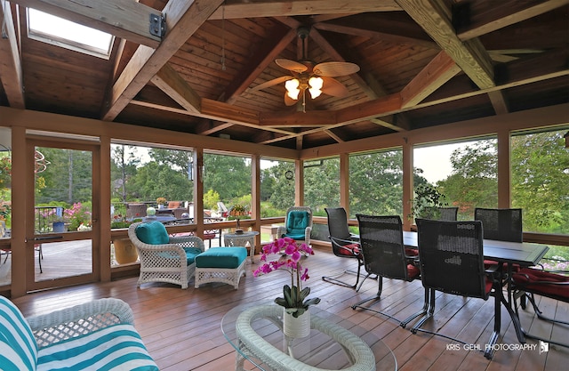 sunroom / solarium with ceiling fan, vaulted ceiling with skylight, and wood ceiling