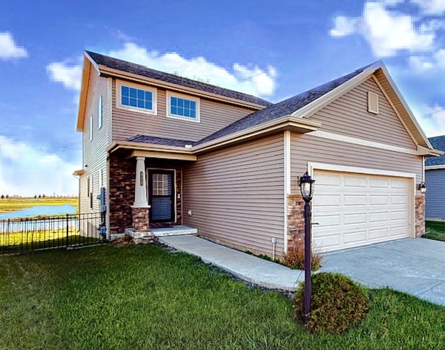 view of front of property with a garage, a water view, and a front yard