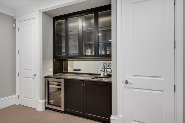 bar featuring wine cooler, dark brown cabinetry, sink, and light carpet