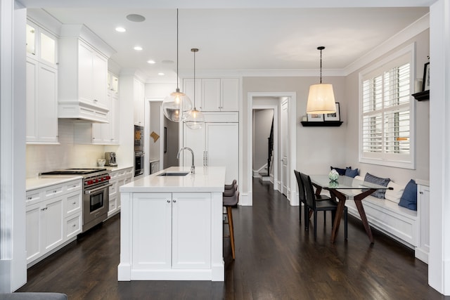 kitchen with white cabinets, premium stove, dark hardwood / wood-style floors, decorative light fixtures, and sink