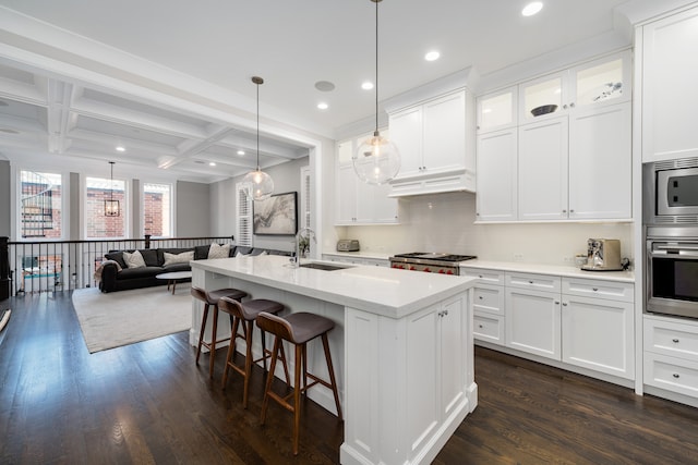 kitchen featuring coffered ceiling, dark hardwood / wood-style floors, a center island with sink, sink, and white cabinetry