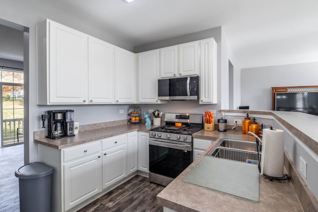 kitchen with white cabinetry, stainless steel appliances, dark wood-type flooring, and sink