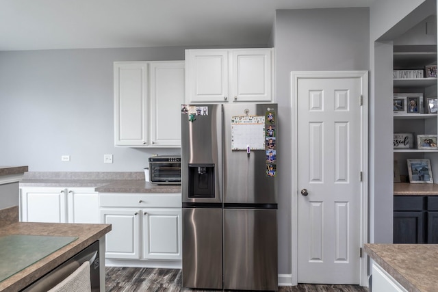 kitchen with stainless steel fridge, white cabinets, and dark wood-type flooring