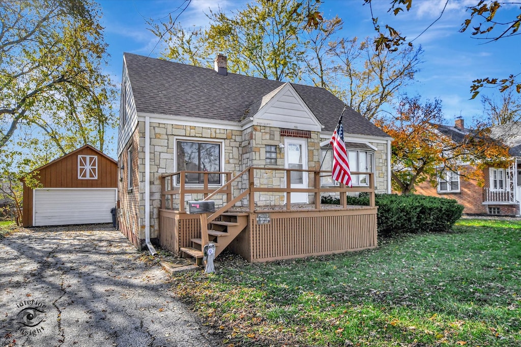 view of front of property featuring a garage, an outdoor structure, and a front yard