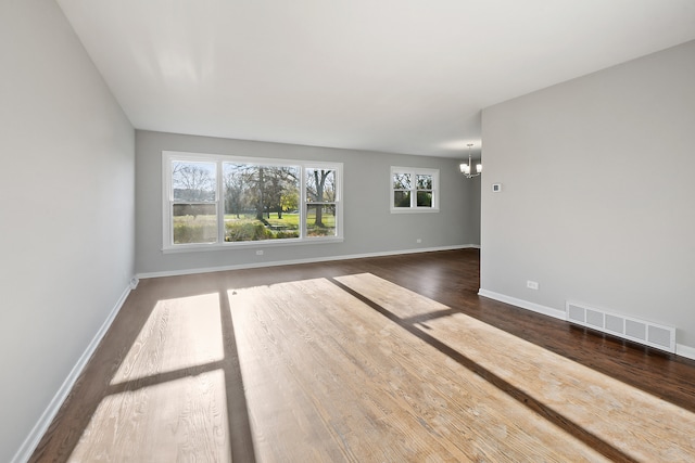 unfurnished room with dark wood-type flooring and an inviting chandelier