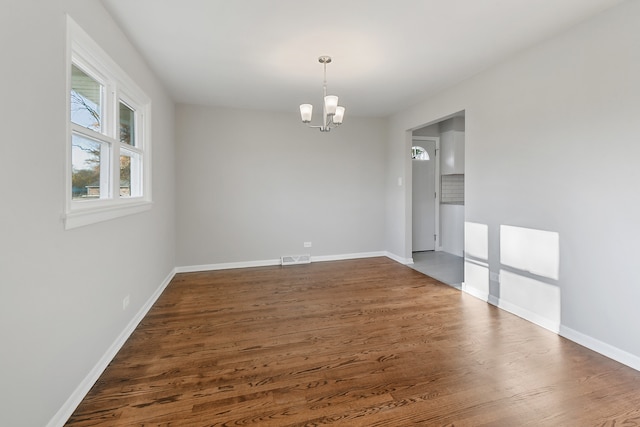 unfurnished room with dark wood-type flooring and a notable chandelier