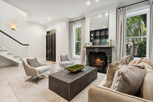 living room featuring crown molding, a healthy amount of sunlight, and a premium fireplace