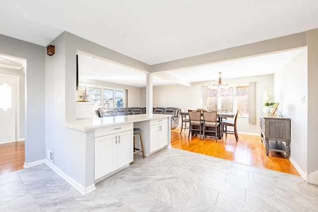 kitchen with white cabinetry, light wood-type flooring, a chandelier, and decorative light fixtures