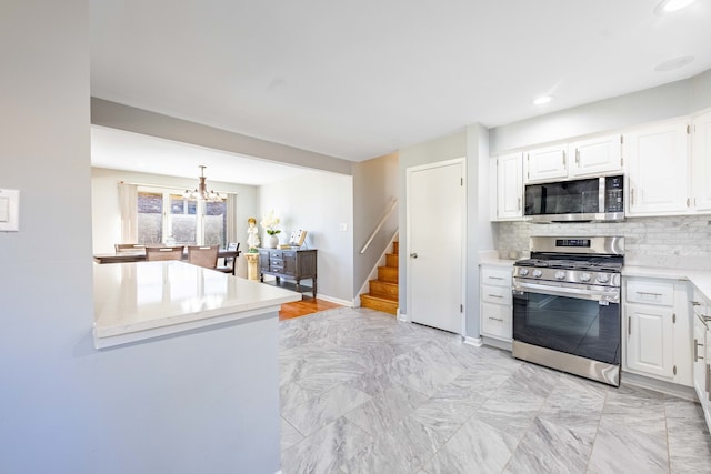 kitchen with appliances with stainless steel finishes, an inviting chandelier, backsplash, decorative light fixtures, and white cabinets