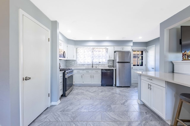 kitchen featuring decorative backsplash, appliances with stainless steel finishes, sink, and white cabinets