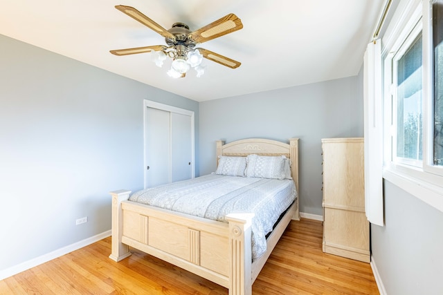 bedroom with light hardwood / wood-style flooring, ceiling fan, and a closet