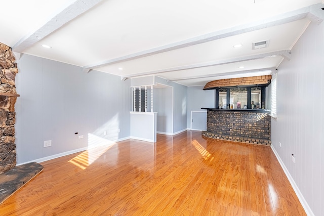 unfurnished living room with bar, hardwood / wood-style flooring, and beam ceiling