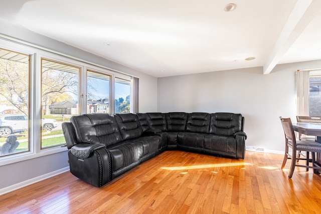 living room featuring beam ceiling and light hardwood / wood-style flooring