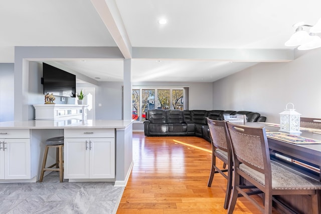 kitchen featuring white cabinets, light wood-type flooring, and beamed ceiling