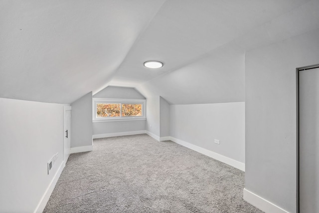 additional living space featuring lofted ceiling and carpet flooring