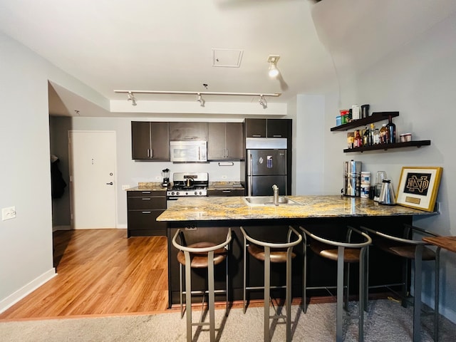 kitchen featuring rail lighting, stainless steel appliances, light hardwood / wood-style flooring, and kitchen peninsula