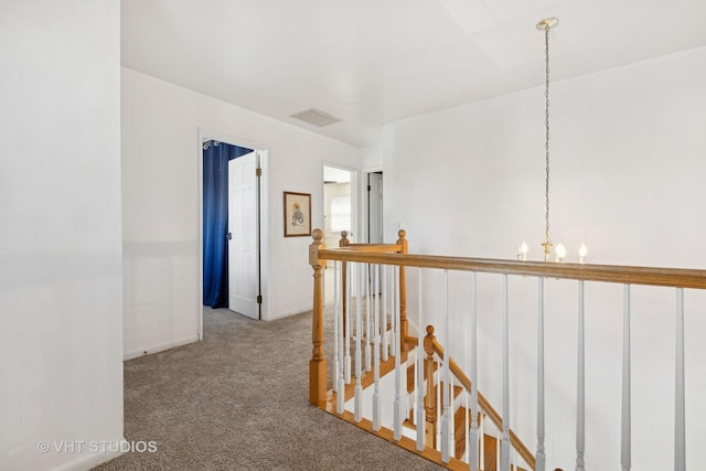 hallway featuring carpet and a notable chandelier