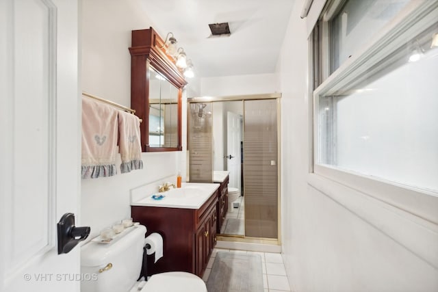 bathroom with tile patterned flooring, vanity, toilet, and a shower with door