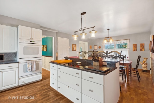 kitchen featuring decorative light fixtures, white cabinetry, a kitchen island, and double oven