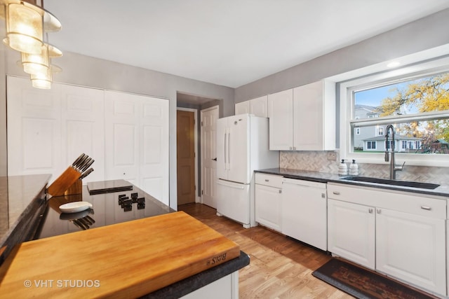 kitchen with white appliances, sink, light wood-type flooring, decorative light fixtures, and white cabinetry