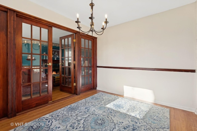 spare room featuring french doors, an inviting chandelier, and hardwood / wood-style flooring