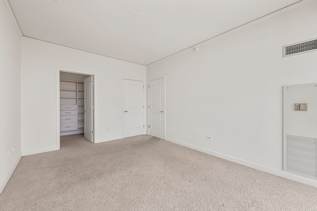 unfurnished bedroom featuring light colored carpet, a walk in closet, and a closet