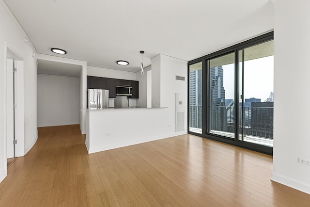 unfurnished living room with floor to ceiling windows and light wood-type flooring