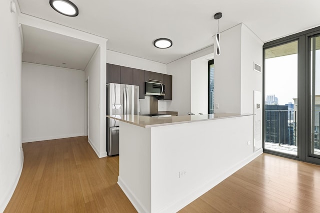 kitchen with expansive windows, dark brown cabinetry, light wood-type flooring, kitchen peninsula, and stainless steel appliances