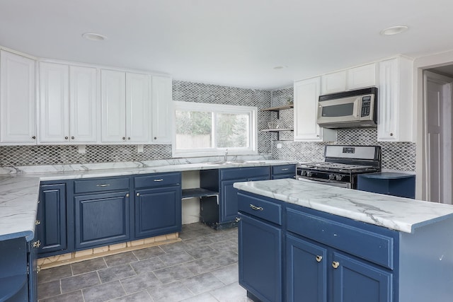 kitchen with blue cabinets, a center island, stainless steel appliances, and white cabinetry