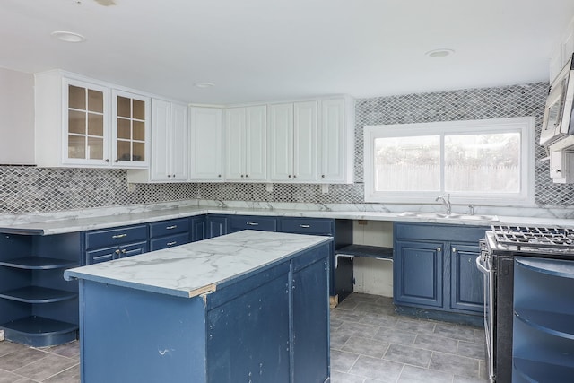 kitchen featuring electric range, blue cabinets, sink, and white cabinetry