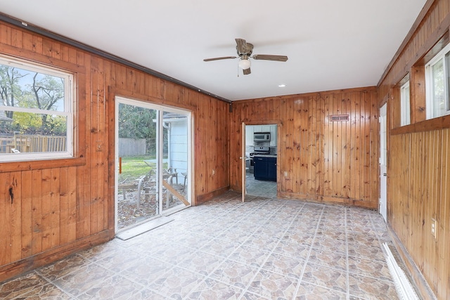 empty room with ceiling fan, crown molding, and wooden walls