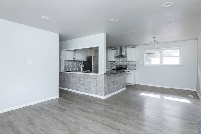 kitchen with wall chimney exhaust hood, hardwood / wood-style flooring, and stainless steel appliances