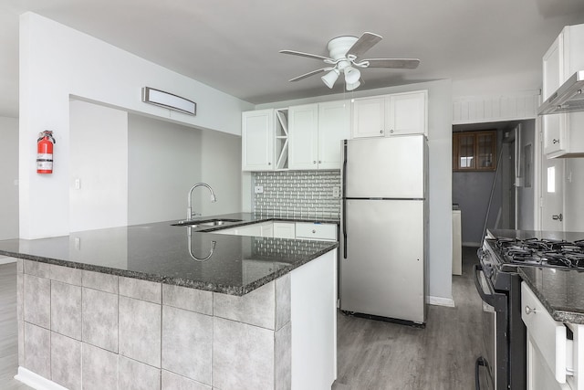 kitchen with appliances with stainless steel finishes, sink, light wood-type flooring, kitchen peninsula, and white cabinets