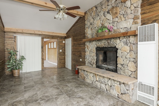 unfurnished living room with wood walls, a stone fireplace, ceiling fan, beam ceiling, and high vaulted ceiling