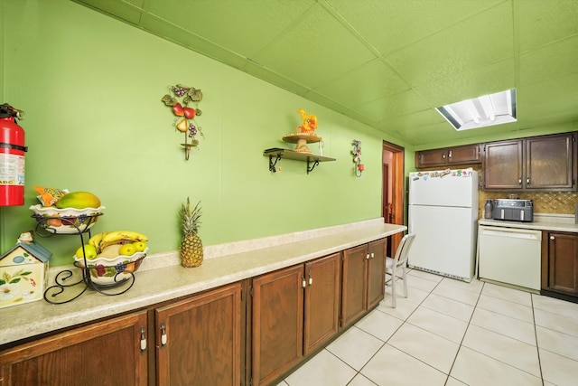 kitchen featuring decorative backsplash, light tile patterned flooring, and white appliances