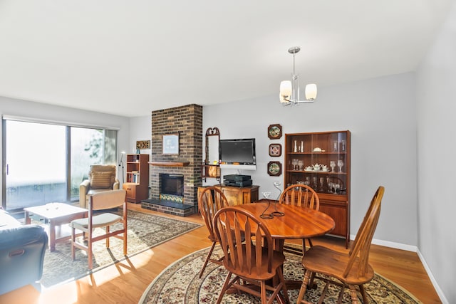 dining room featuring a notable chandelier, wood-type flooring, and a fireplace