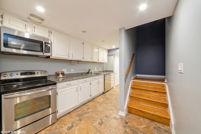 kitchen with sink, white cabinets, stainless steel appliances, and dark stone counters