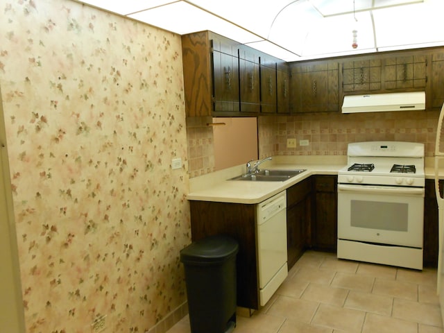 kitchen featuring decorative backsplash, sink, dark brown cabinets, and white appliances