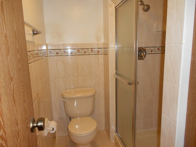 bathroom featuring a shower with door, tile walls, toilet, and tile patterned flooring