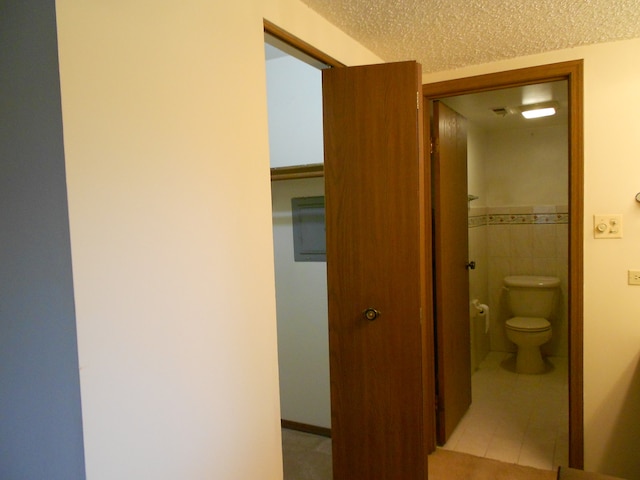 bathroom featuring toilet, tile patterned floors, and a textured ceiling