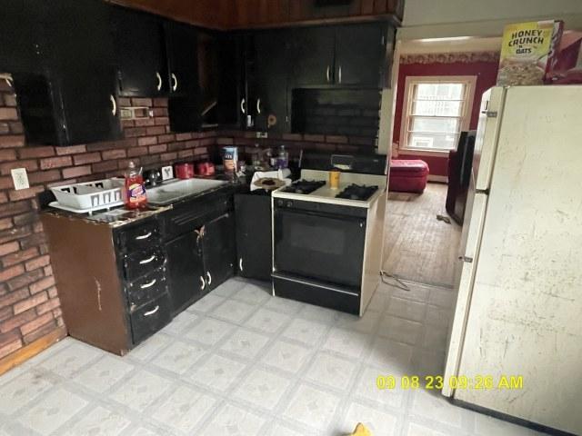 305 River Oaks Dr, Calumet City, IL 60409 - kitchen featuring freestanding refrigerator, dark cabinets, light floors, and range with gas cooktop