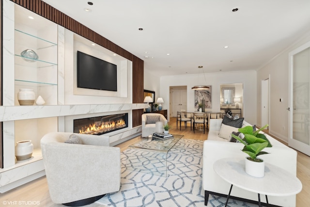 living room with light hardwood / wood-style floors, crown molding, and a fireplace