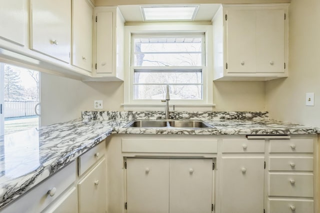 kitchen featuring white cabinets, sink, and a skylight