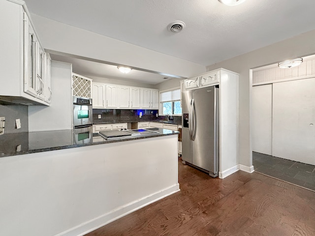 kitchen with backsplash, kitchen peninsula, dark hardwood / wood-style flooring, white cabinetry, and stainless steel appliances