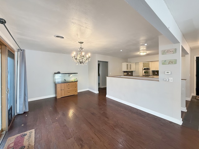 unfurnished living room featuring dark hardwood / wood-style flooring and a chandelier