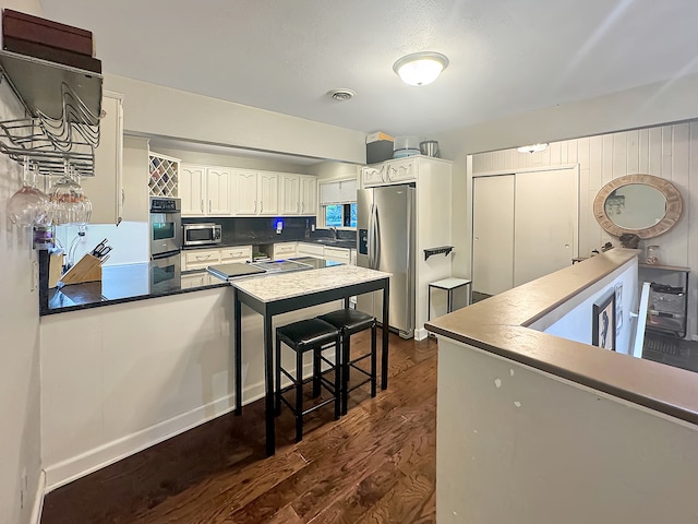 kitchen featuring backsplash, dark wood-type flooring, white cabinets, sink, and appliances with stainless steel finishes